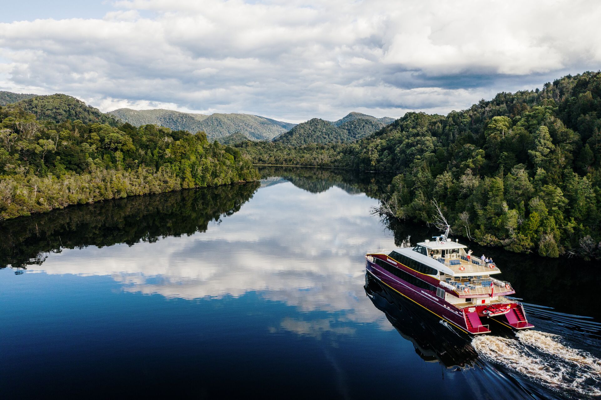 A boat travelling down a river surrounded by forest 