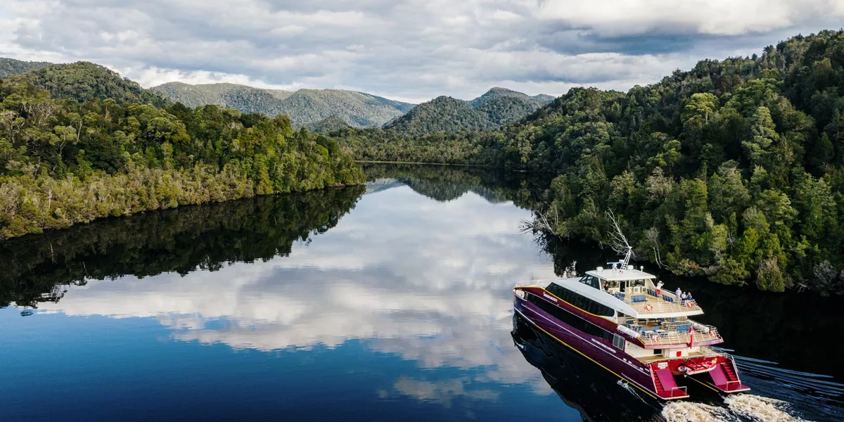 A boat travelling down a river surrounded by forest